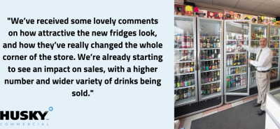 Large refrigerator units displaying drinks. An employee in white shirt and tie inspects the stocked shelves in a bright, modern store.