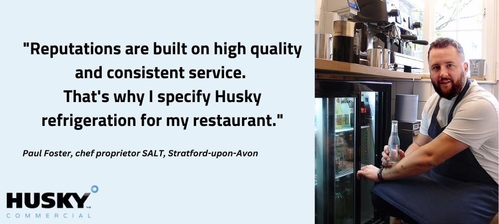 A man in a kitchen holds a bottled drink, kneeling next to a refrigerated cabinet. Text: "Reputations are built on high quality and consistent service. That's why I specify Husky refrigeration for my restaurant."
