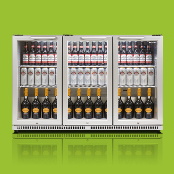 A triple-door refrigerator displays bottled beverages, including beer and sparkling wine, neatly arranged on shelves. The refrigerator is set against a bright green background, with "Husky" branding on the top right.