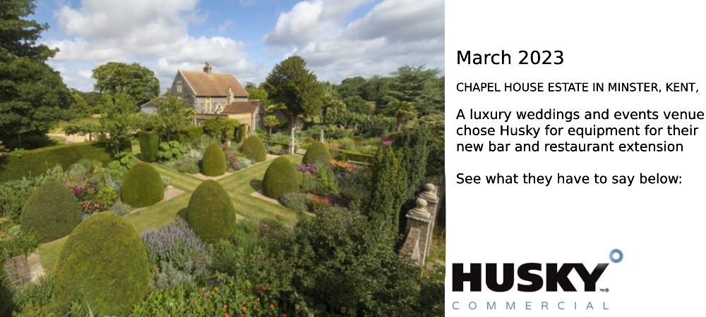 A quaint cottage surrounded by a meticulously landscaped garden with neatly trimmed topiary bushes and vibrant flowerbeds; lush greenery and tall trees provide a serene backdrop. Text: "HUSKY COMMERCIAL" in the bottom right corner.