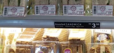 Packaged sandwiches are displayed on refrigerated shelves, labeled "Shitake Chicken," "Mushroom," and "Egg." The bottom shelf has a sign reading "Assorted SANDWICH RM 3.50 each," with some packs labeled "NEW!"