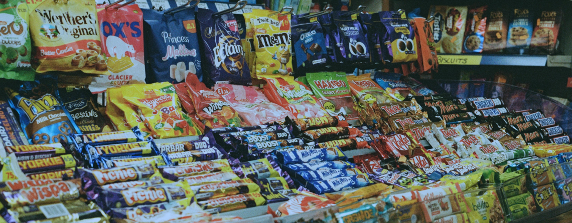 A vibrant display of chocolate bars, crisps, and confectionery in a convenience store, showcasing impulse purchase items. Perfect for store owners optimizing product placement.