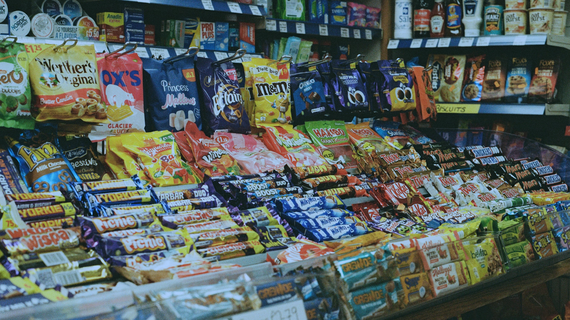A vibrant display of chocolate bars, crisps, and confectionery in a convenience store, showcasing impulse purchase items. Perfect for store owners optimizing product placement.