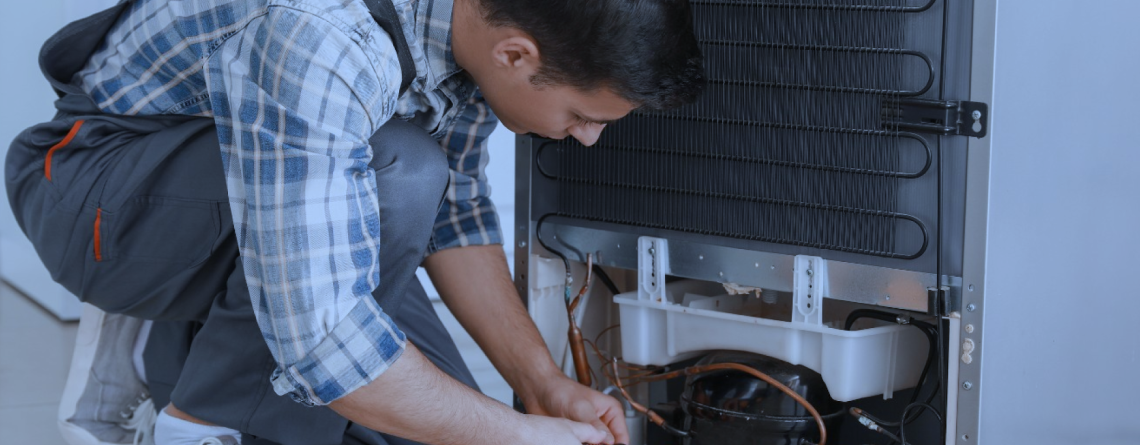 A skilled engineer kneeling and repairing a commercial fridge, performing routine maintenance to ensure optimal cooling performance and energy efficiency.
